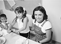 teacher with two girls, one making a sandwich
